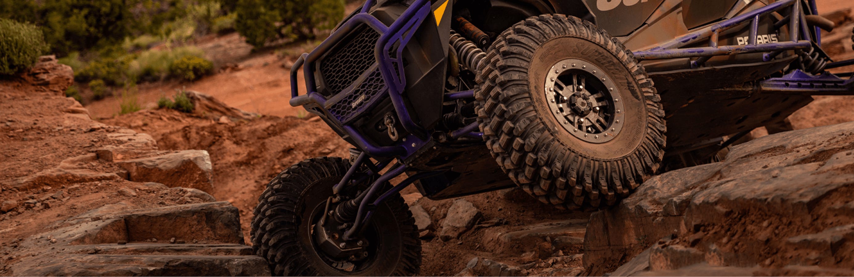 Purple and black Polaris RZR with GDP Portal Gear Lifts installed climbing rocks